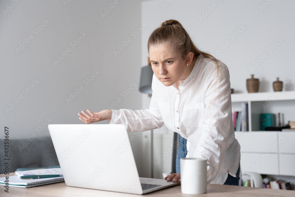 Surprised young woman spying coworker's laptop Surprised young woman spying coworker's laptop