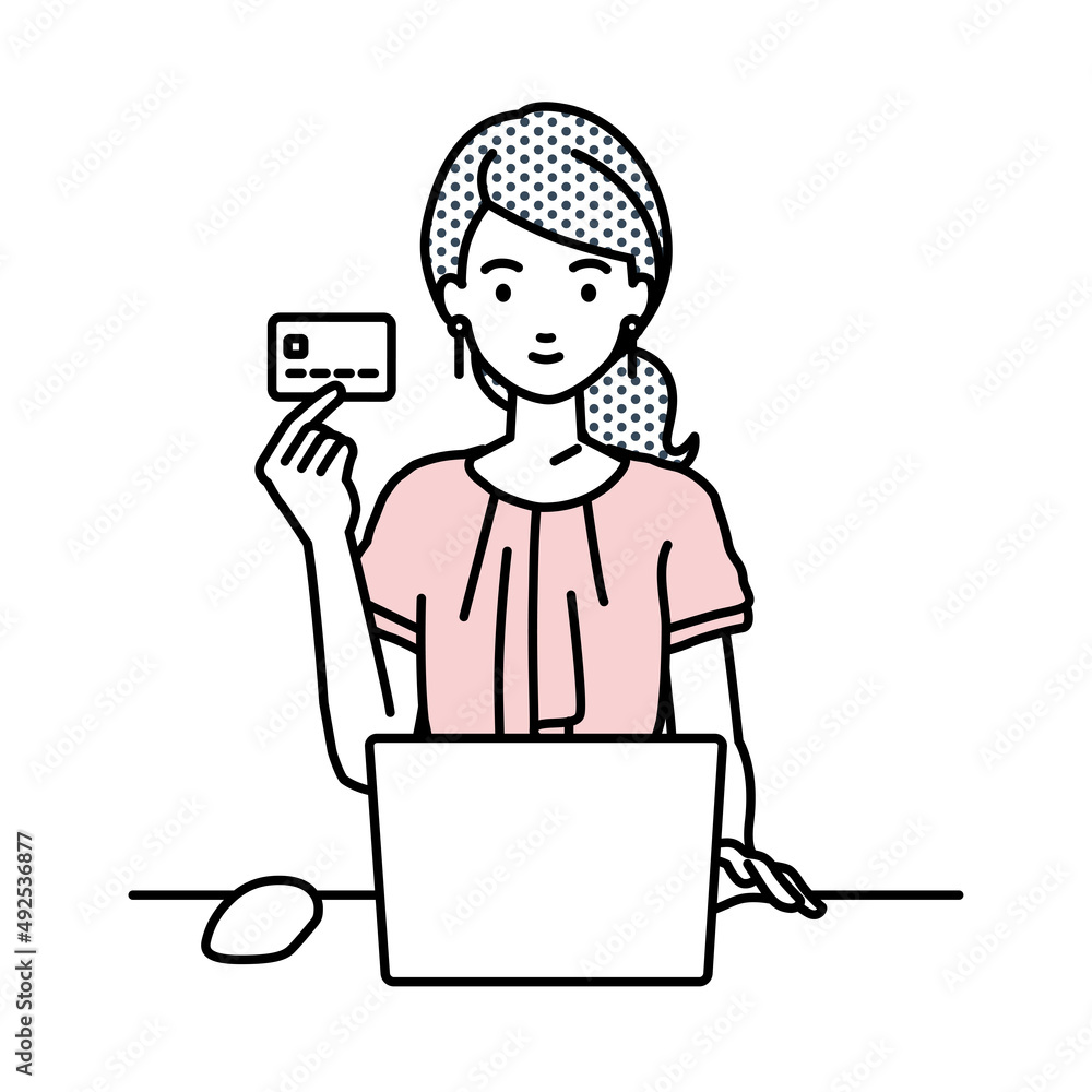 デスクで座ってPCを使いながらクレジットカードを手に持っているオフィスカジュアルの女性
