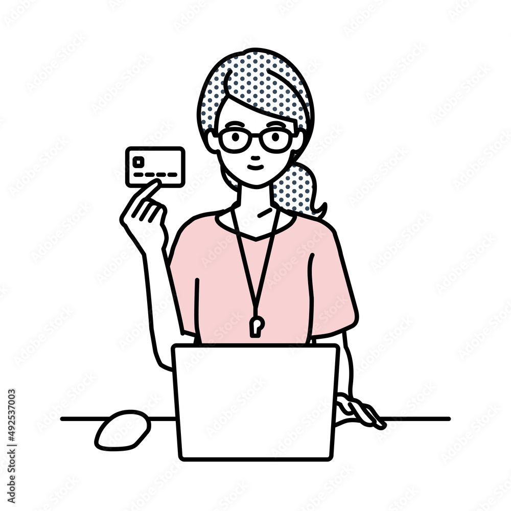 デスクで座ってPCを使いながらクレジットカードを手に持っている教師の女性
