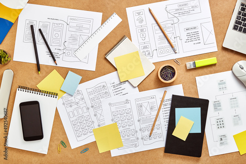 Top view image of web product designers workspace with many website wireframe sketches and sitemap.