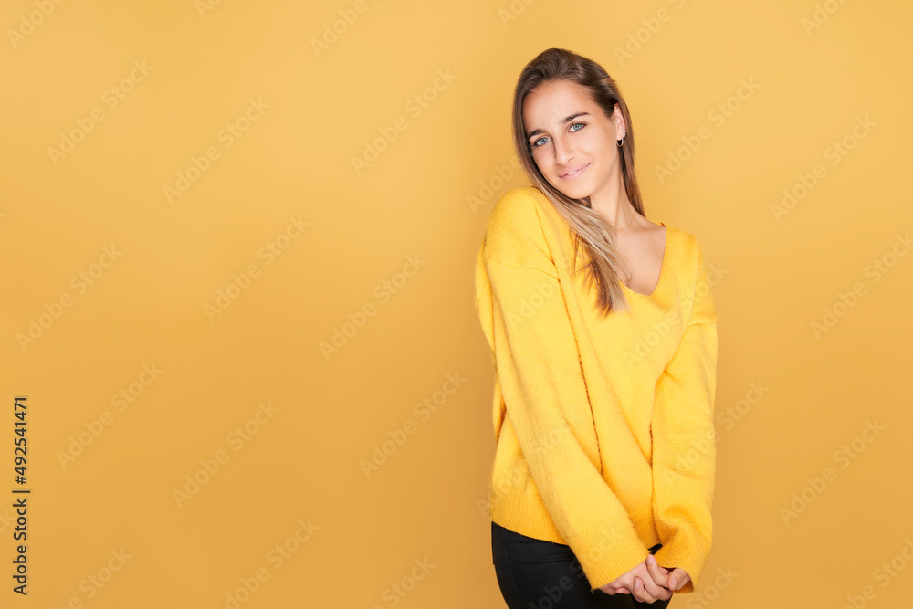 Shy young girl in yellow sweater. isolated on yellow background Shy young girl in yellow sweater. isolated on yellow background
