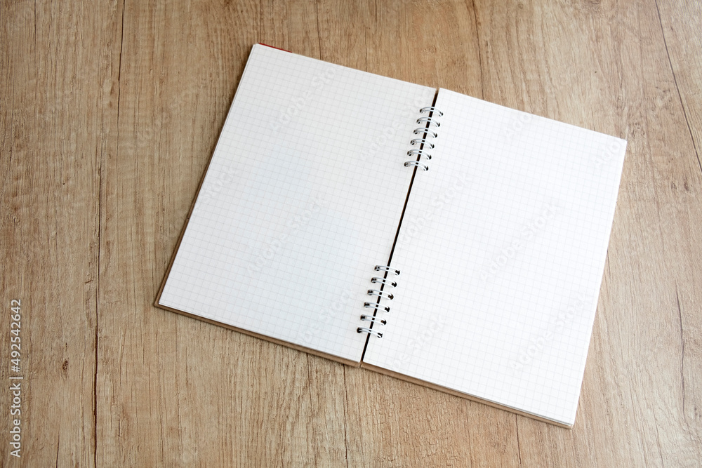Open checkered notepad on a wooden table Open checkered notepad on a wooden table