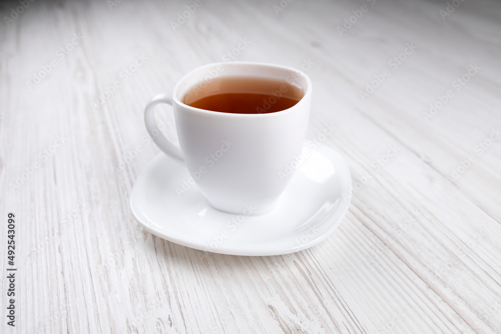 White cup with black tea on a wooden table, side view White cup with black tea on a wooden table, side view