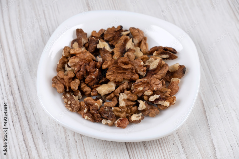 Walnuts on a white plate, side view. Walnut kernels on the table. Healthy food Walnuts on a white plate, side view. Walnut kernels on the table. Healthy food