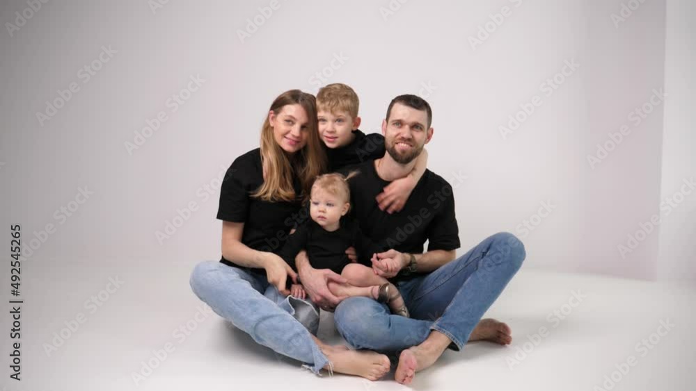 Happy family sit posing together mother and father, a boy son and toddler little daughter enjoy together Happy family sit posing together mother and father, a boy son and toddler little daughter enjoy together