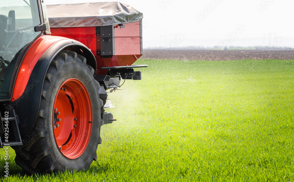 Tractor spreading artificial fertilizers in field Tractor spreading artificial fertilizers in field
