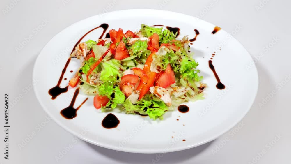 Healthy Eating. Salad for dieting. Spring salad of fresh greens and tomatoes lying on a white plate and rotating. Healthy Eating. Salad for dieting. Spring salad of fresh greens and tomatoes lying on a white plate and rotating.