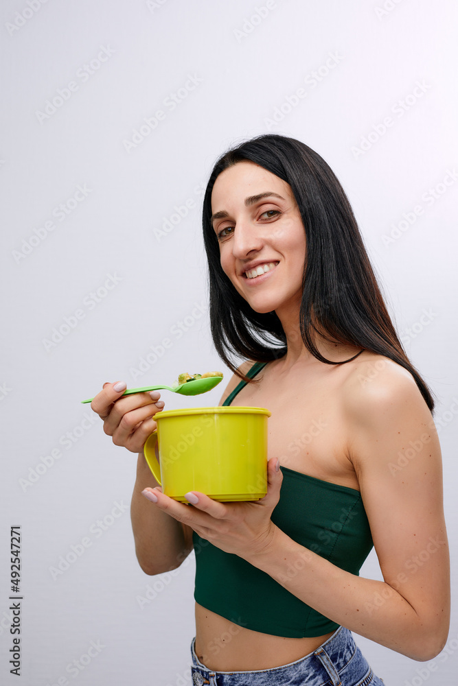 Young model healthy woman eating green vegetables avocado, cucumber and green herbs. Detoxification, vegetarian, healthy eating and diet concept Young model healthy woman eating green vegetables avocado, cucumber and green herbs. Detoxification, vegetarian, healthy eating and diet concept