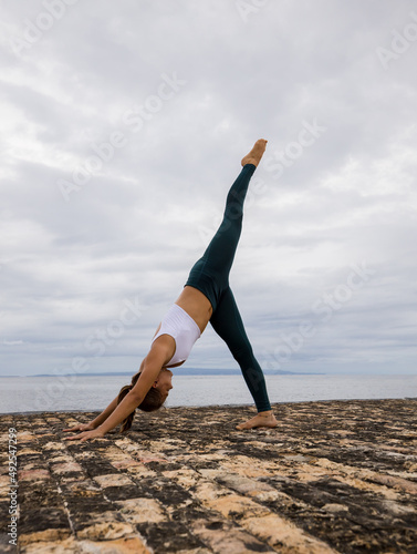 Flexible young woman practicing gymnastic exercise. Parvatasana, Mountain pose. One leg up. Strong body, straight back. Healthy lifestyle. Yoga retreat. Copy space. Bali
