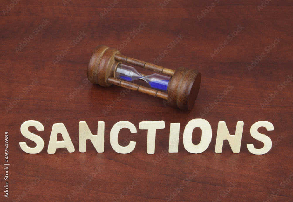 Hourglass and word sanction on wooden background. Sanction time concept. Hourglass and word sanction on wooden background. Sanction time concept.