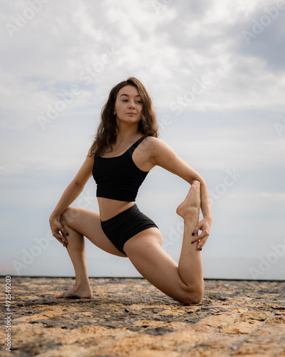 Workout on the beach. Sport, fitness, wellness concept. Attractive sportive woman workouts outdoor. Healthy lifestyle. Strong fit body. Woman wearing black sportswear. Copy space. Bali