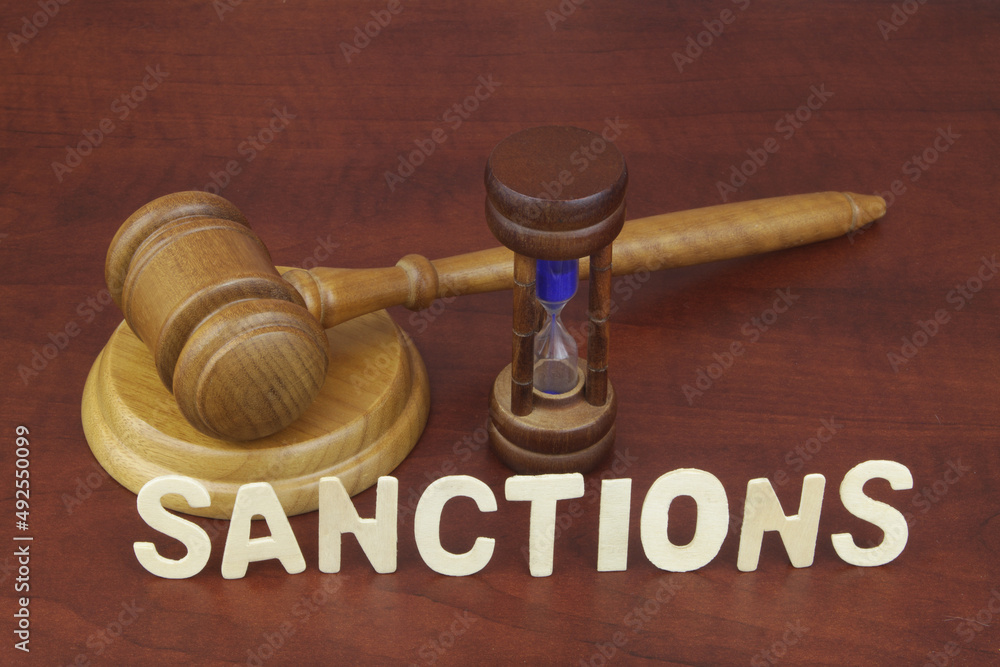 Wooden judge gavel with hourglass and word sanctions. Wooden judge gavel with hourglass and word sanctions.