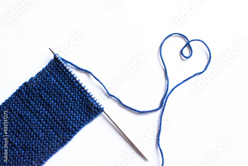 Unfinished wool and knitting needle design. Blue thread and tangle. Handmade concept. Craft banner. Love, romantic, valentines day concept. Thread in heart shape Isolated. Top view. Copy space