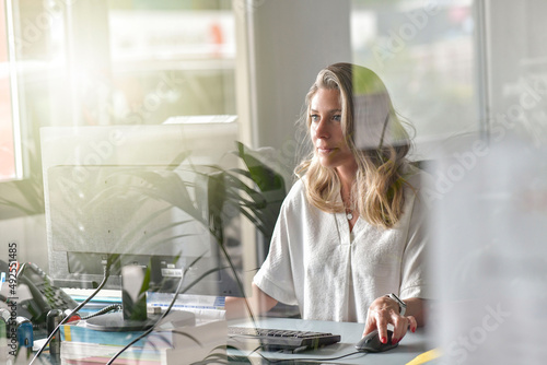 Through-window view of woman working in office photo