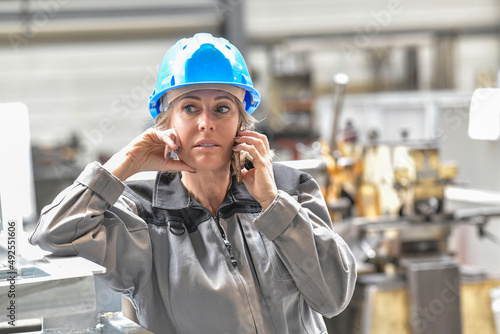 Woman at work in engineering plant, using smartphone photo