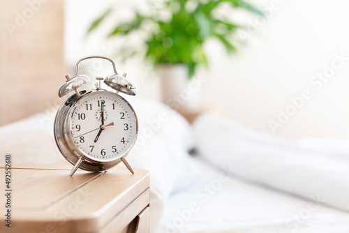 Alarm clock morning wake-up time on bedside table background