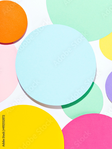 Fun bright coloured mosaic of paper circles in pink, blue, yellow and purple colours. Minimalist background in pastel tones. Creative conceptual template for styling and design. Mock up for text.