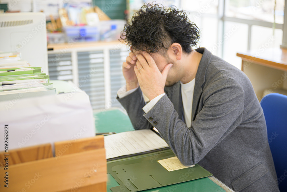 残業が大変で職員室で悩む先生 素材庫相片 | Adobe Stock