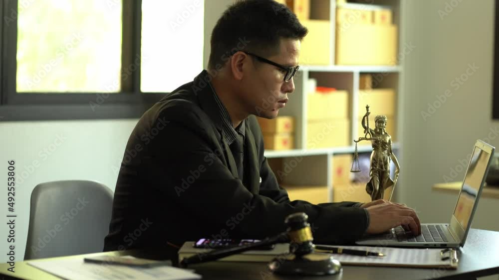 concept of justice and law A male lawyer works in an office with a brass scale goddess on a wooden table. Justice hammer with laptop Legal Concepts and Legal Services concept of justice and law A male lawyer works in an office with a brass scale goddess on a wooden table. Justice hammer with laptop Legal Concepts and Legal Services