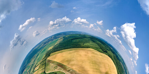 Aerial view from high altitude of little planet earth with yellow cultivated agricultural fields with ripe wheat and green woods on bright summer day