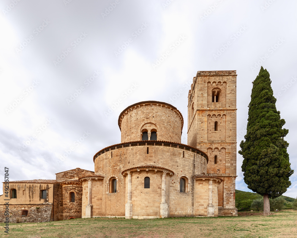 The ambulatory with radial chapels, belltower, and cypress in Abbey Sant Antimo. Val d'Orcia, Tuscany, Italy