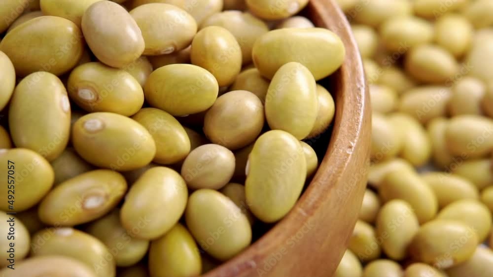 Full wooden bowl with uncooked peruvian bean. Falling mayocoba grains. Macro. Canary legumes. Slow motion Full wooden bowl with uncooked peruvian bean. Falling mayocoba grains. Macro. Canary legumes. Slow motion