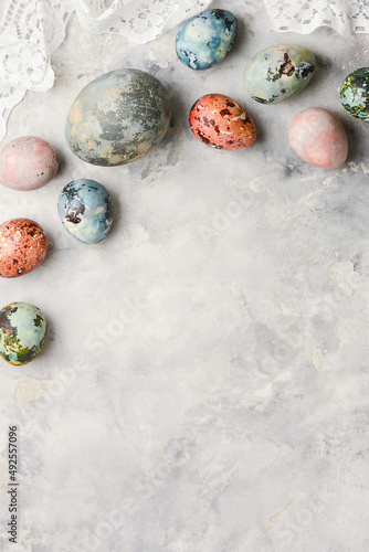 Spring holiday Easter concept. Multicolored painted eggs on a concrete light gray background with copy space for text. Vertical banner.