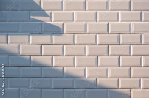 Sunlight and shadow on surface of white tile wall background © Prapat
