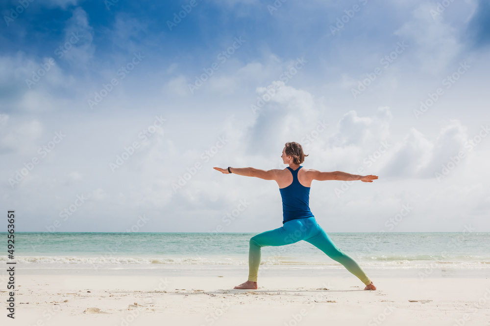 Caucasian woman practicing yoga at seashore