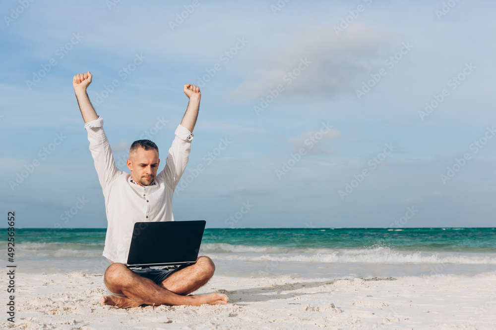 Successful Young man using laptop computer on the beach. Relaxation Vacation Working Outdoors Beach Concept