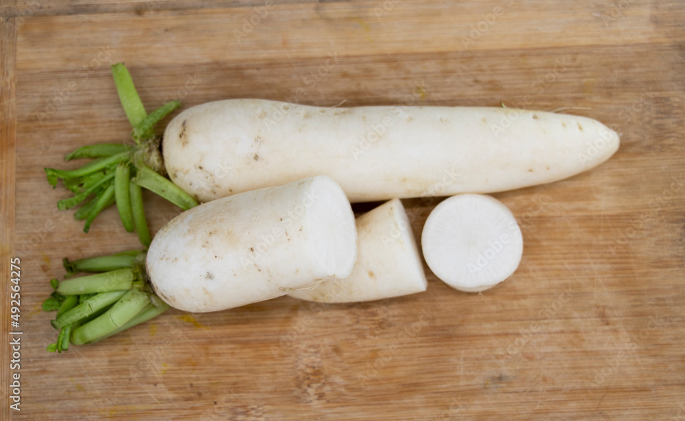 whole and slices white radishes isolated on wooden background.
