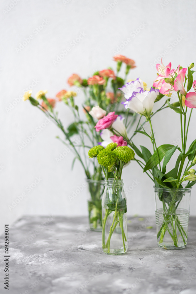 Colorful flowers composition over grey background with copy space. Fresh cut flowers for decoration home. Flower arrangement in a vase for home. Women's Day and spring time flower background