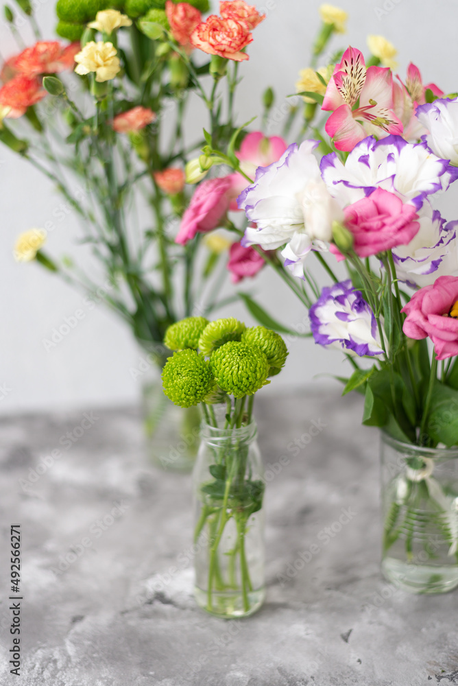Colorful flowers composition over grey background with copy space. Fresh cut flowers for decoration home. Flower arrangement in a vase for home. Women's Day and spring time flower background Colorful flowers composition over grey background with copy space. Fresh cut flowers for decoration home. Flower arrangement in a vase for home. Women's Day and spring time flower background