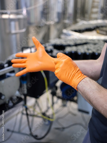 Vertical photo of a worker putting on latex gloves in a brewery