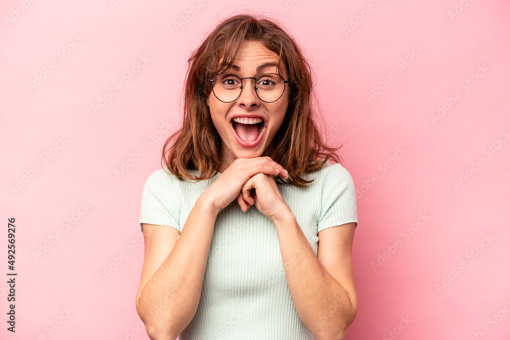 Young caucasian woman isolated on pink background praying for luck, amazed and opening mouth looking to front. Young caucasian woman isolated on pink background praying for luck, amazed and opening mouth looking to front.