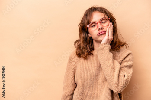 Young caucasian woman isolated on beige background who feels sad and pensive, looking at copy space.