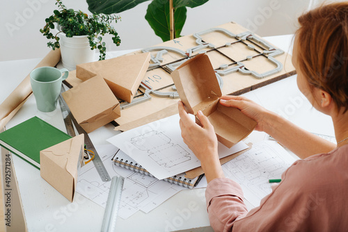 Woman holding a box in hands, thinking process on ways to improve it.