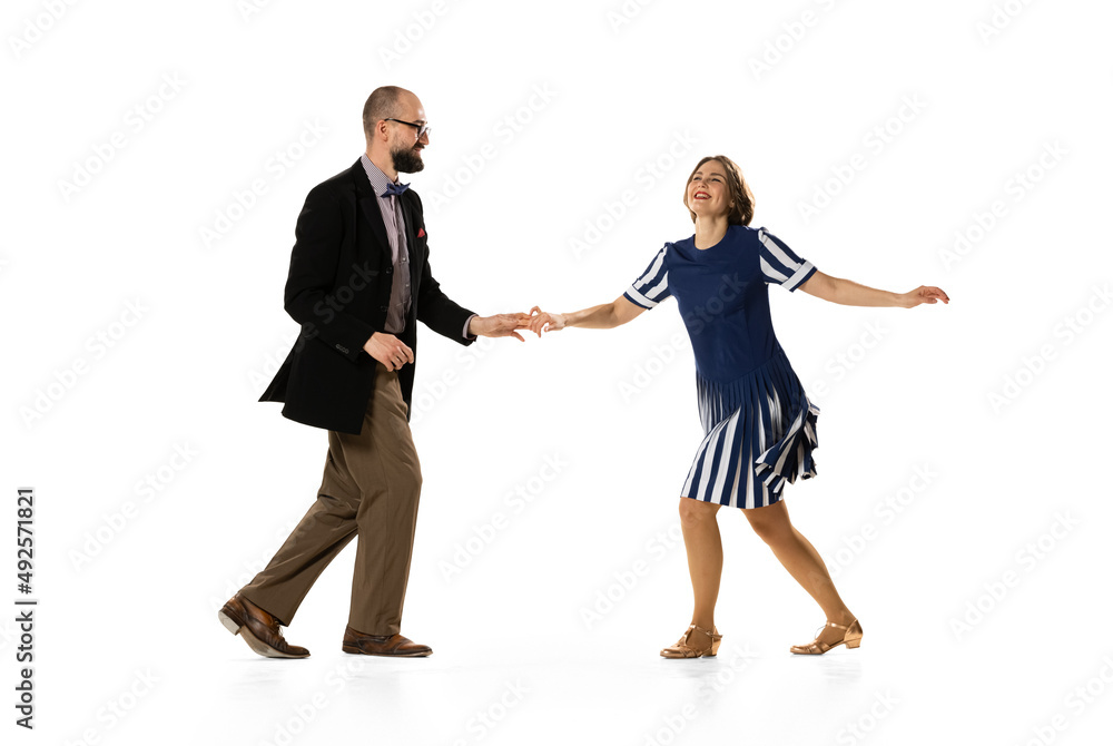Couple of dancers, young man and woman in vintage retro style outfits dancing swing dance isolated on white background. Timeless traditions, 60s, 70s fashion style.