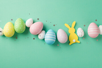 Top view photo of easter decorations shiny confetti row of multicolored easter eggs and easter bunny silhouette on isolated turquoise background with copyspace