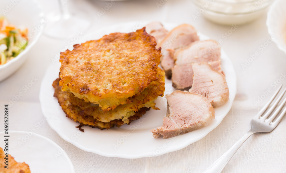 Potato pancakes with meat on white plate