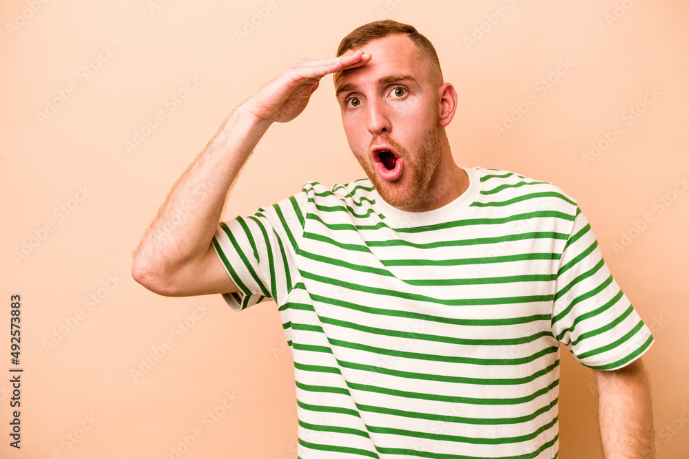 Young caucasian man isolated on beige background shouts loud, keeps eyes opened and hands tense. Young caucasian man isolated on beige background shouts loud, keeps eyes opened and hands tense.
