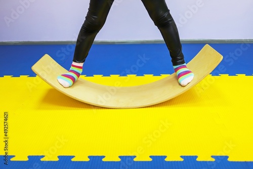 a little girl in white swings on a special balance beam to the sides in a children's center so as not to get sick
