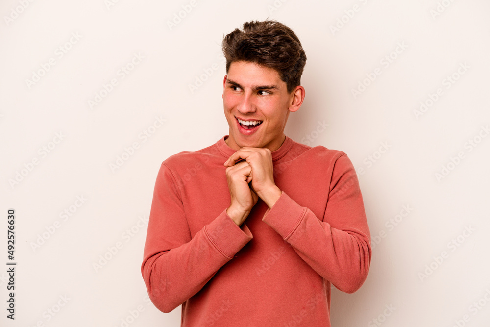 Young caucasian man isolated on white background praying for luck, amazed and opening mouth looking to front. Young caucasian man isolated on white background praying for luck, amazed and opening mouth looking to front.
