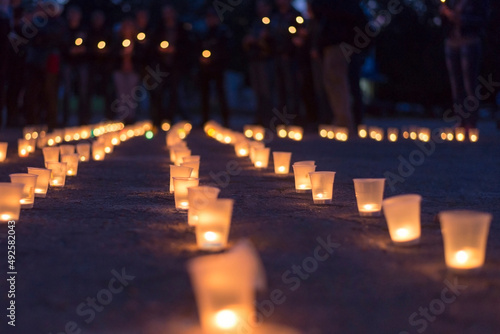 A group of candles burning in street and people in the background.