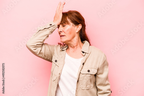 Foto Middle age caucasian woman isolated on pink background forgetting something, slapping forehead with palm and closing eyes