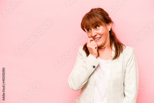 Middle age caucasian woman isolated on pink background relaxed thinking about something looking at a copy space.