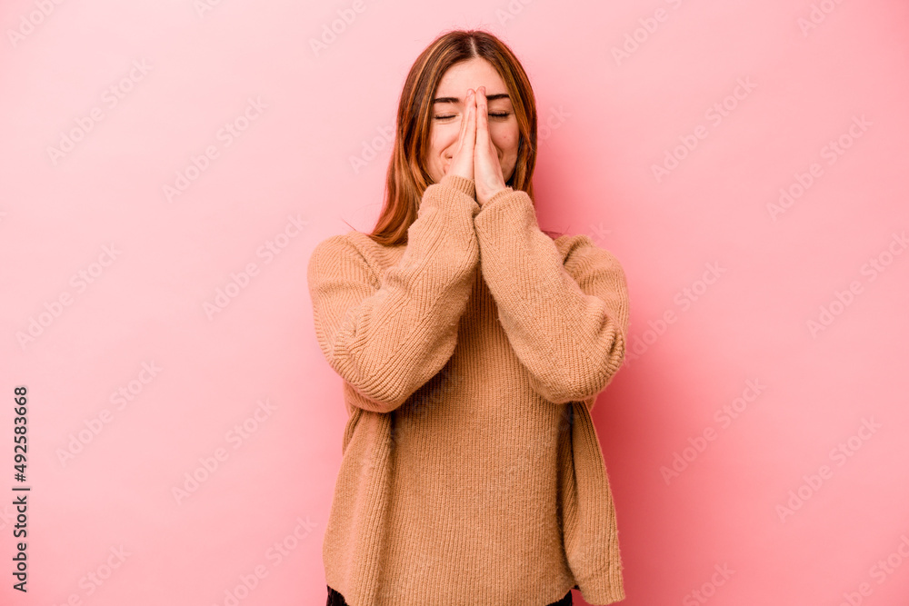 Young caucasian woman isolated on pink background holding hands in pray near mouth, feels confident. Young caucasian woman isolated on pink background holding hands in pray near mouth, feels confident.