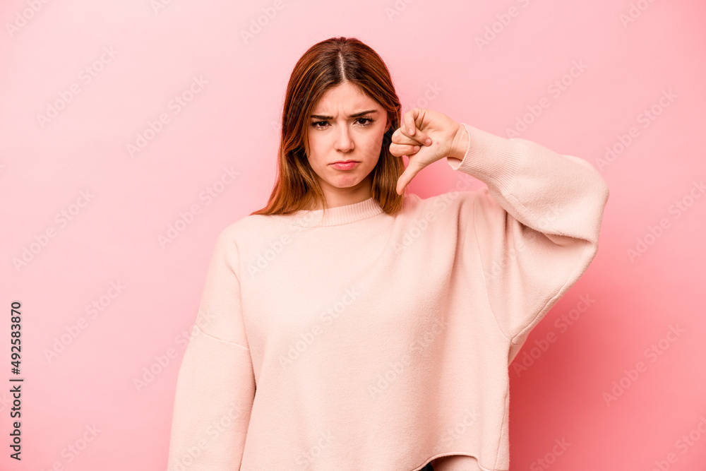 Young caucasian woman isolated on pink background showing thumb down, disappointment concept. Young caucasian woman isolated on pink background showing thumb down, disappointment concept.