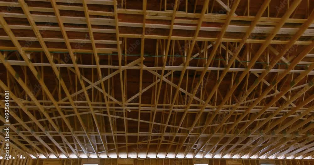 New built home under construction roof with wooden truss, post and beam framework roof on stick New built home under construction roof with wooden truss, post and beam framework roof on stick