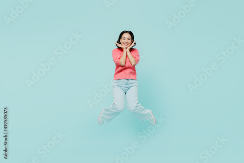 Fototapeta Naklejka Na Ścianę i Meble -  Full body young smiling fun happy woman of Asian ethnicity 20s wearing pink sweater jumpo high hold face isolated on pastel plain light blue color background studio portrait. People lifestyle concept.